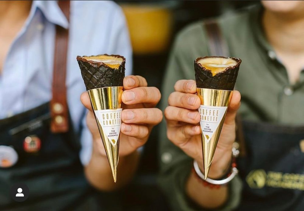two ice cream cones held by baristas