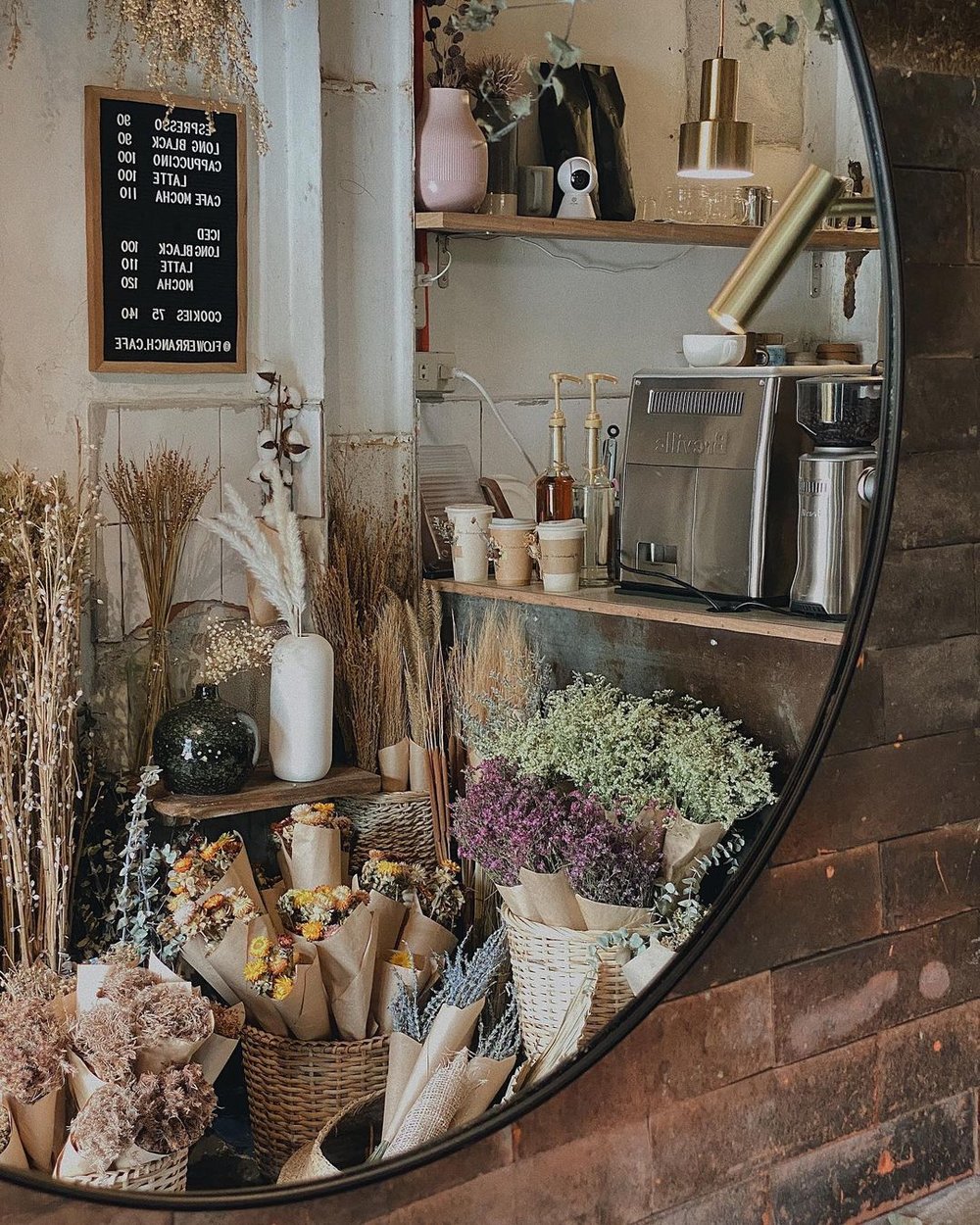 reflection of dried flowers by cafe counter on mirror