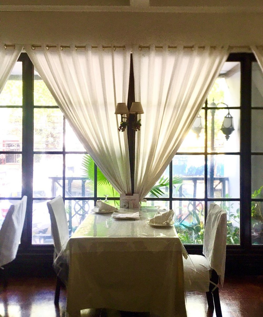 table for two by the window with white curtains