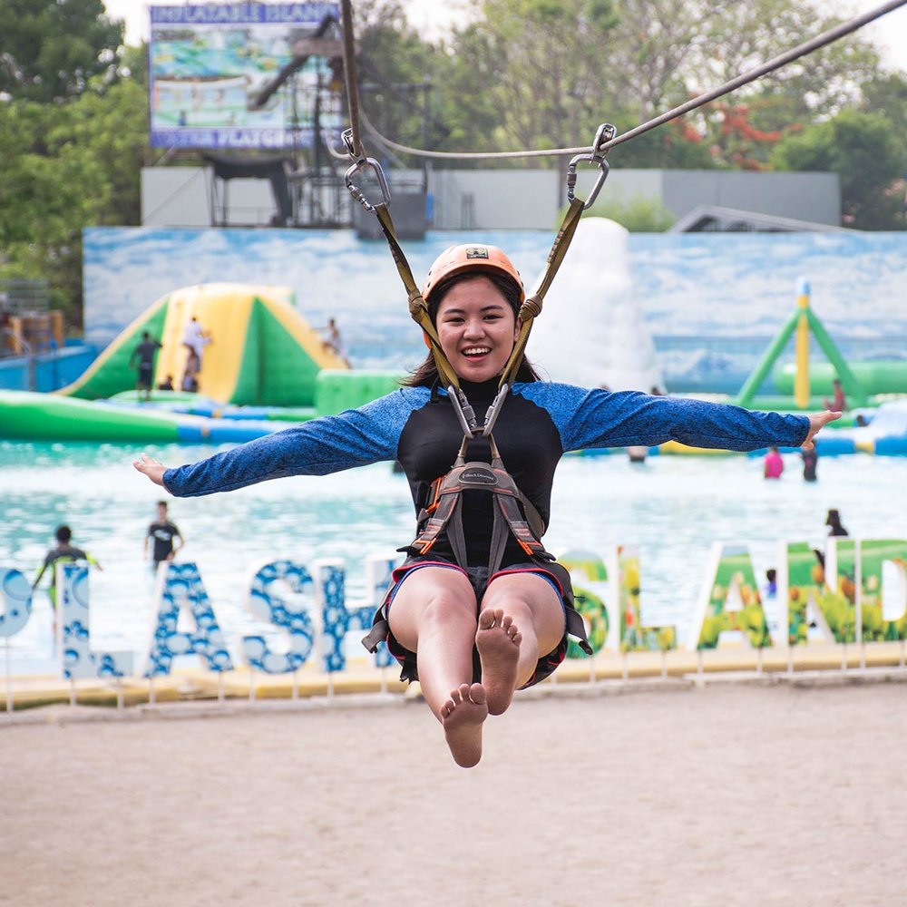 girl on zipline above swimming pool