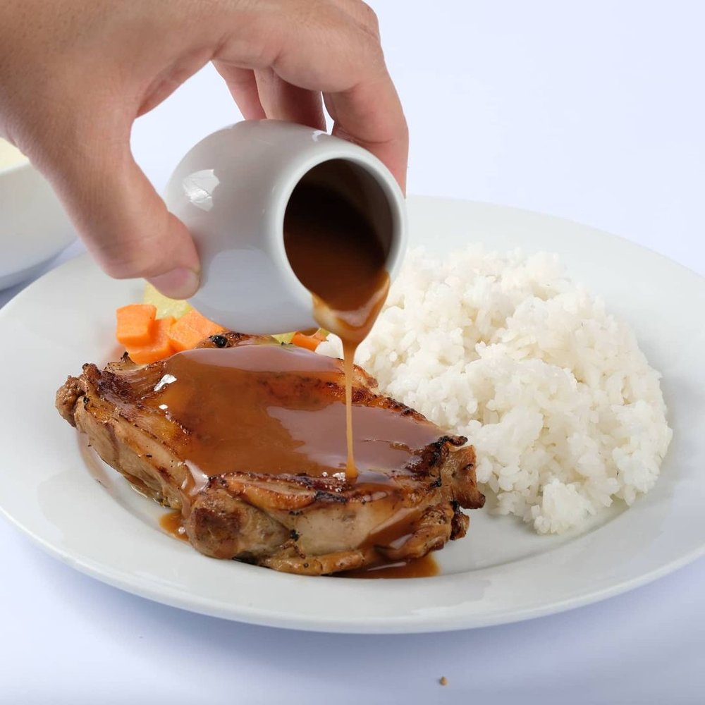 gravy being poured on meat and rice