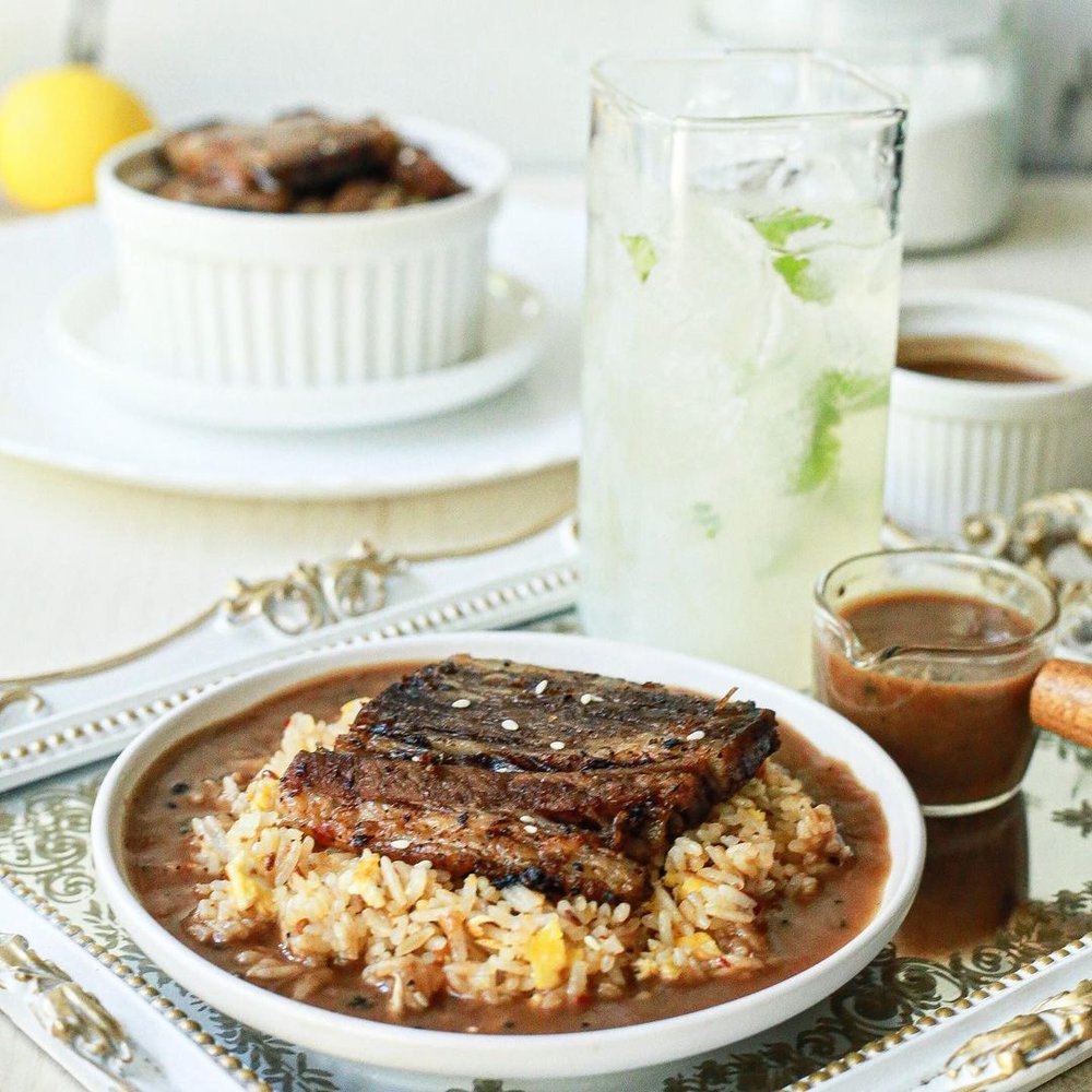 meat on bed of rice plated in formal dinnerware
