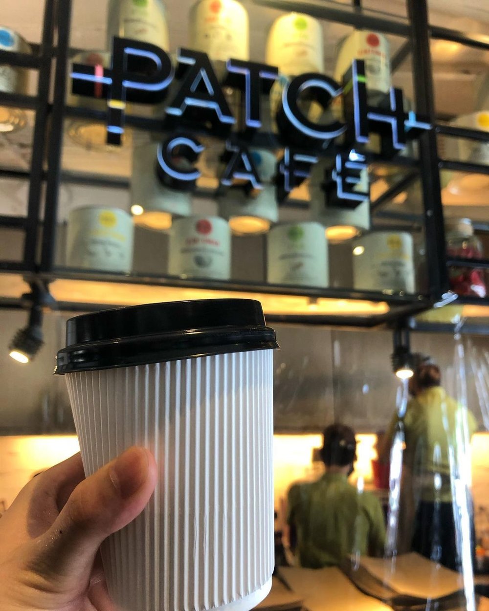 cup holding coffee in front of cafe sign
