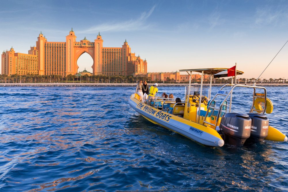 dubai yellow boat sightseeing tour with tourists onboard in front of palm jumeirah