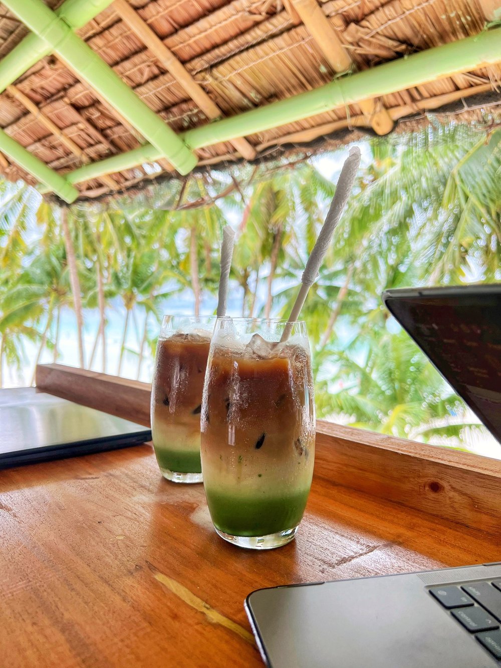 two iced matcha lattes by beach bar