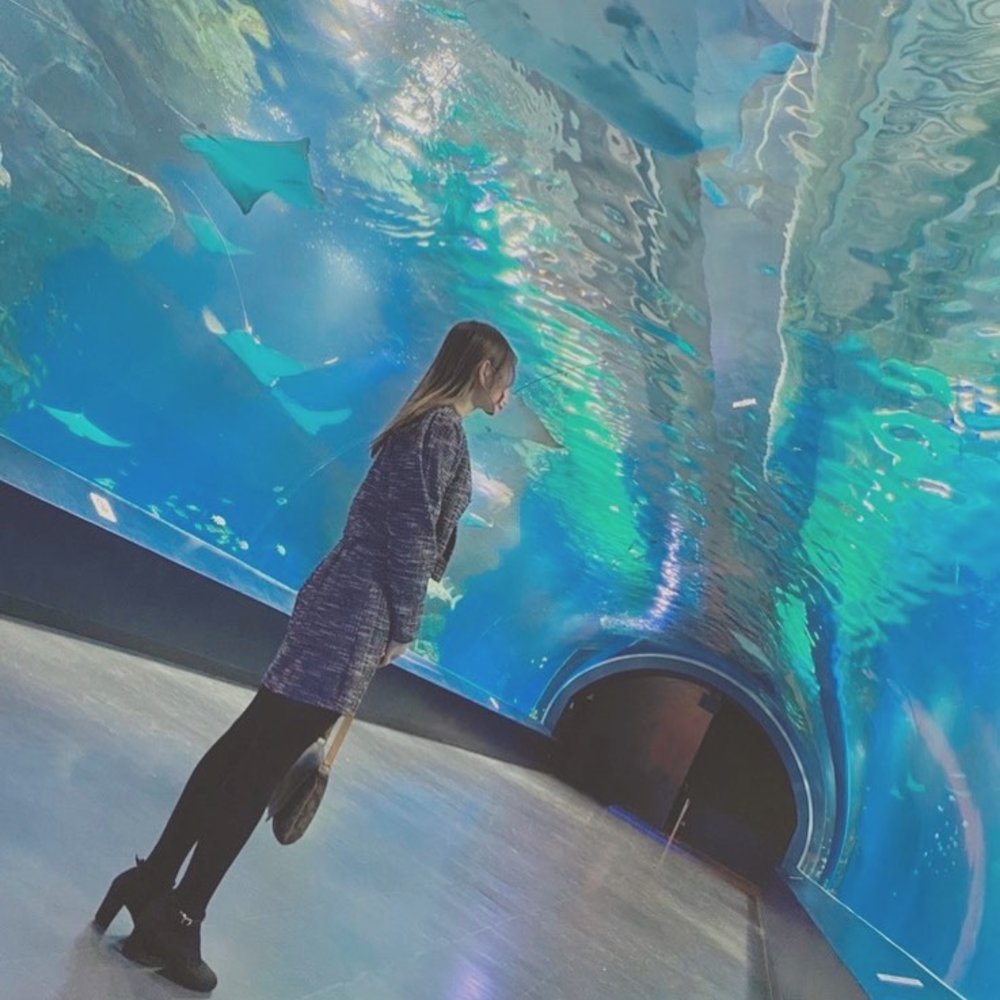 トンネル型水槽の間に斜めに立つ女性