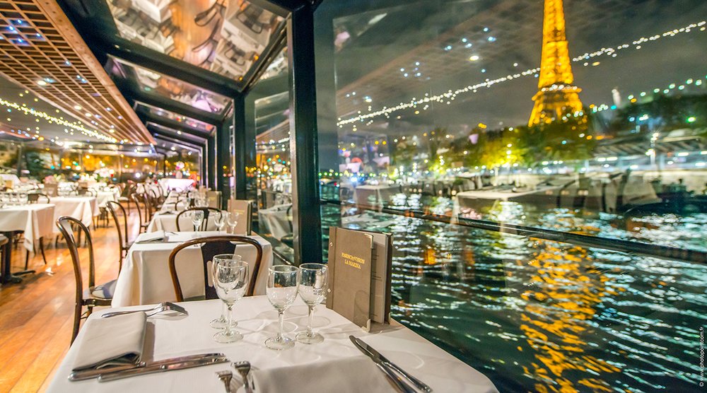 a romantic dinner by the windows of a floating restaurant on paris' river seine