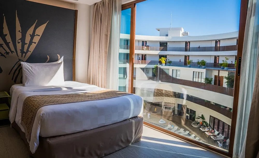 hotel bed next to window with pool view