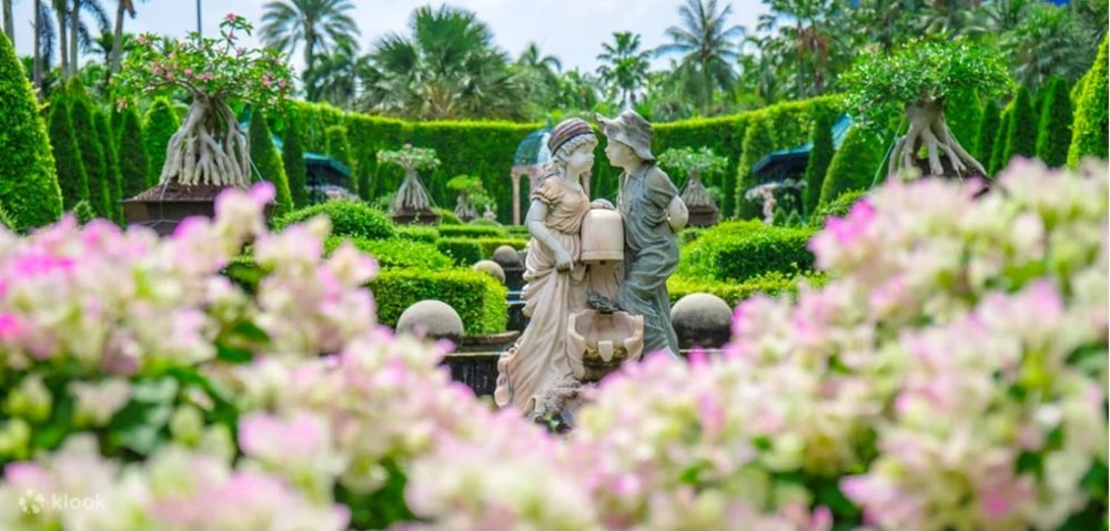 two statue in a garden full of flowers