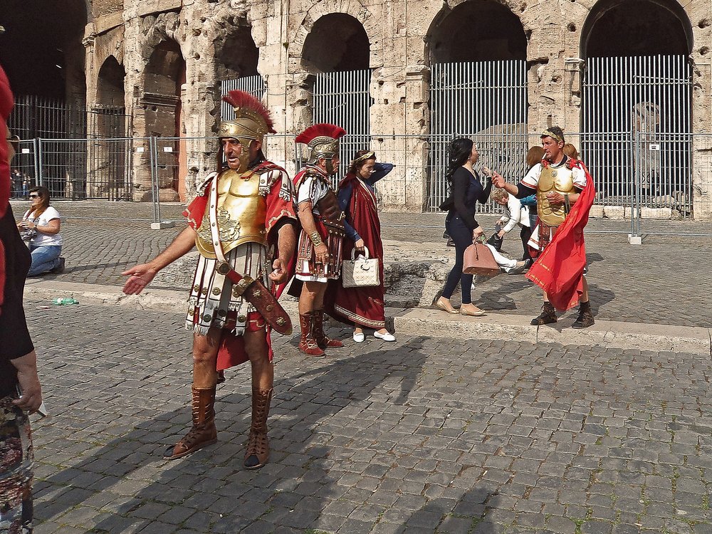 a group of men in centurion costumes in front of Rome's Colosseum