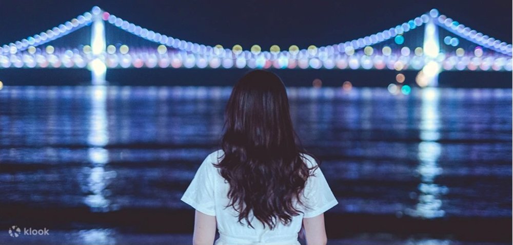 Girl watching the colorful bridge at night