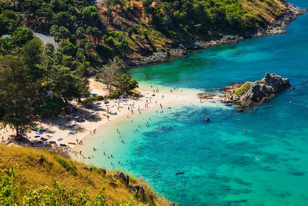 Crystal blue waters, rock formation, and many tourists at Promthep Cape and Nui Beach