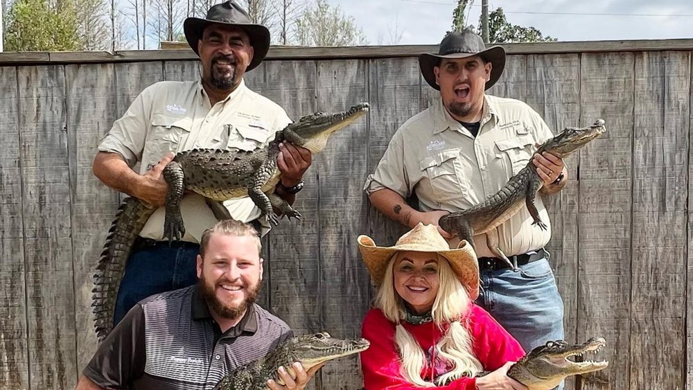 People posing for a photo while carrying alligators
