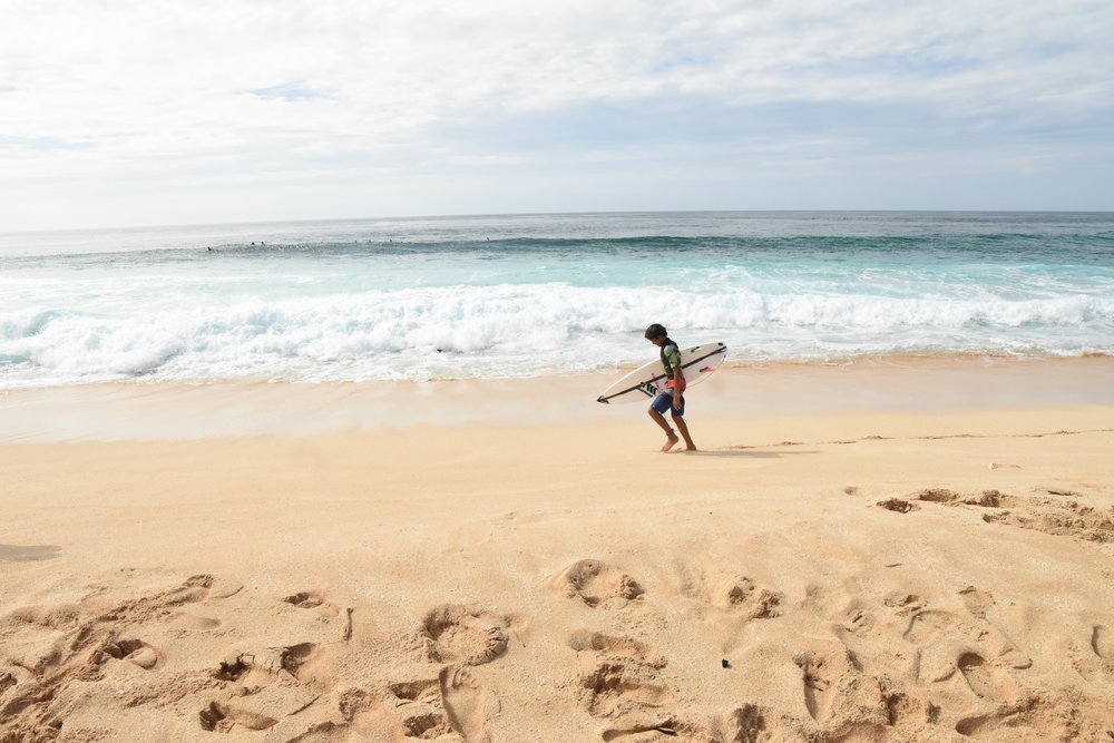 Surfer walking on Banzai Pipeline