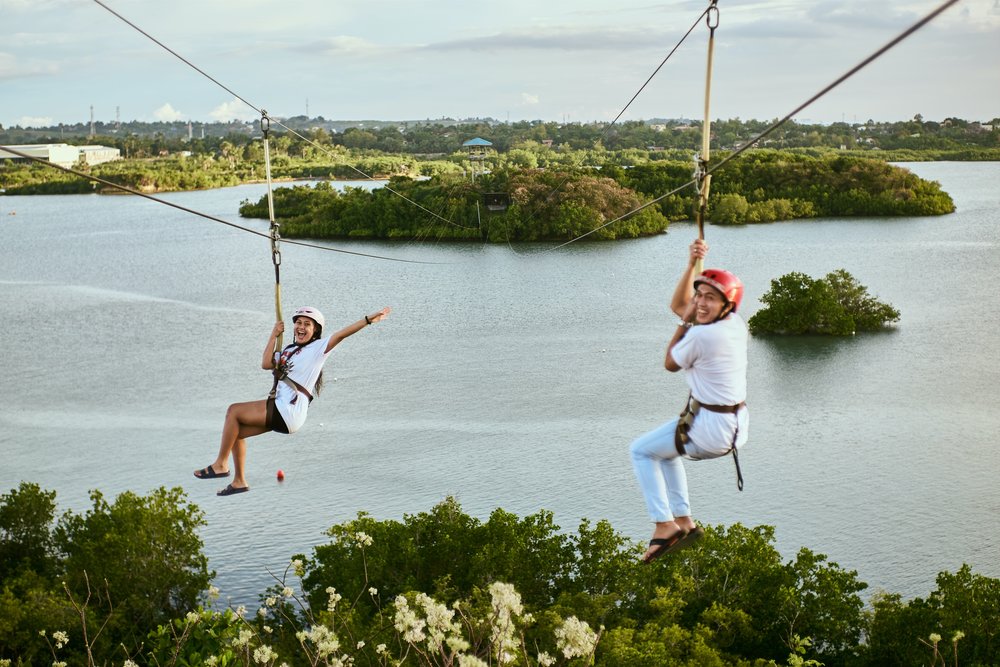 Two travelers happily trying the zip line