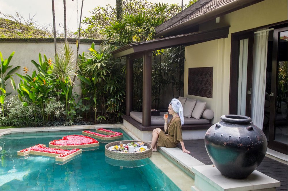 Girl in the pool sipping wine while having lunch