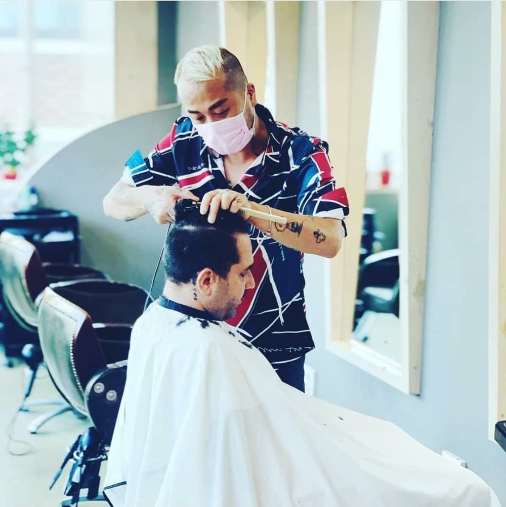 Hairdresser cutting guy's hair