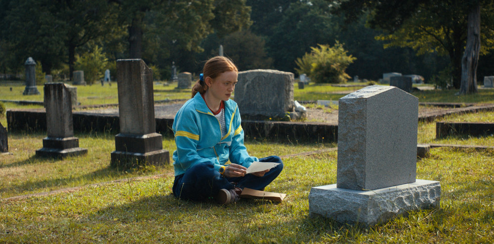 red head girl sitting in front of grave