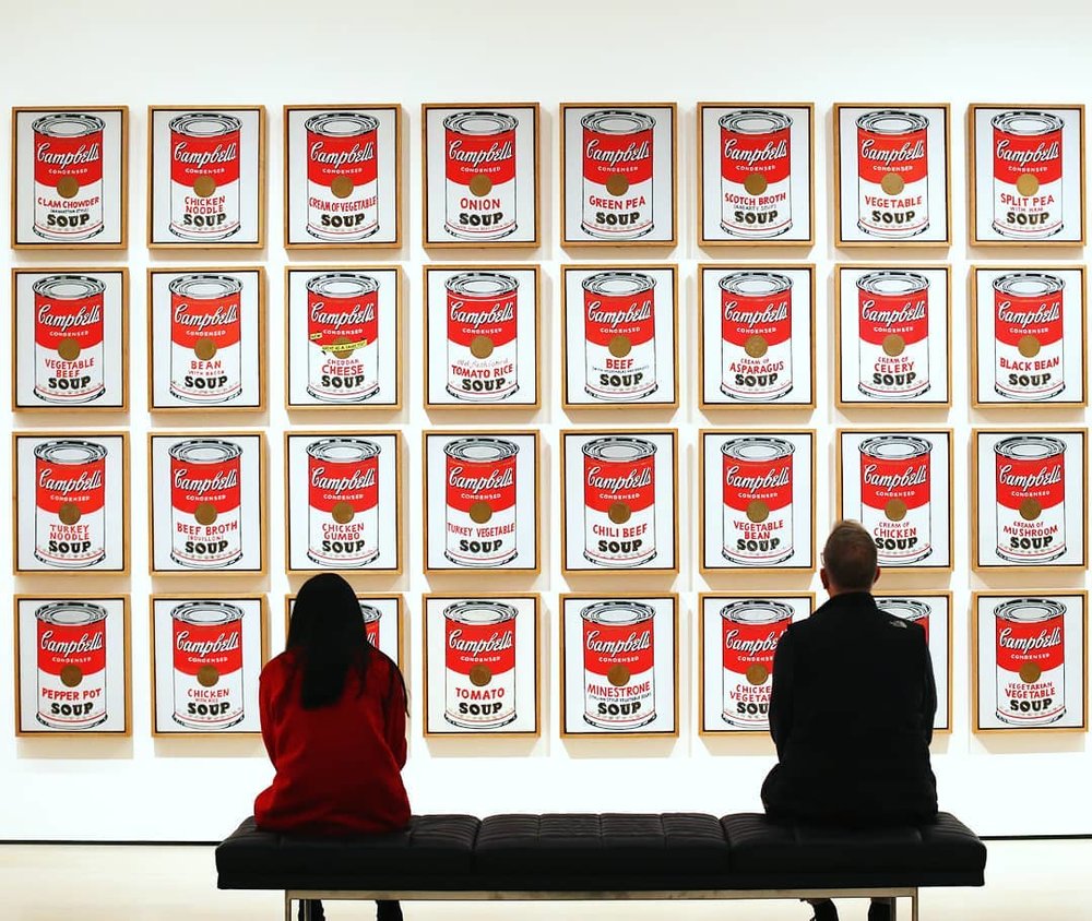 people looking at an artwork showing campbells chicken soup cans