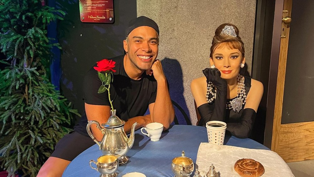 Visitor posing for a photo with Audrey Hepburn's wax figure in Madame Tussauds New York