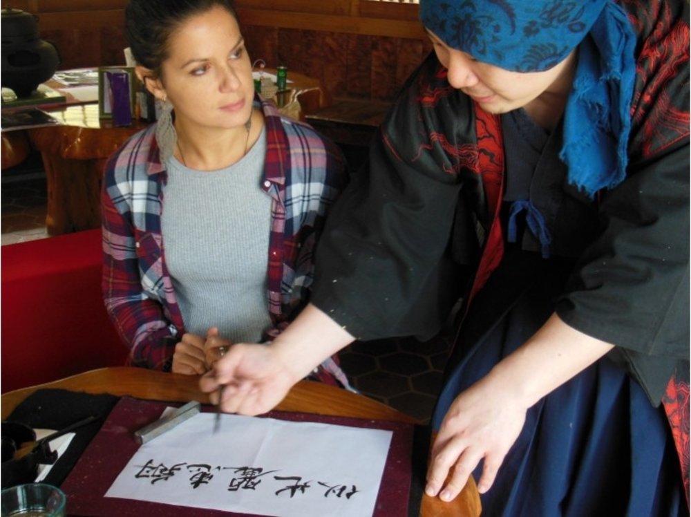 girl learning japanese calligraphy with instructor