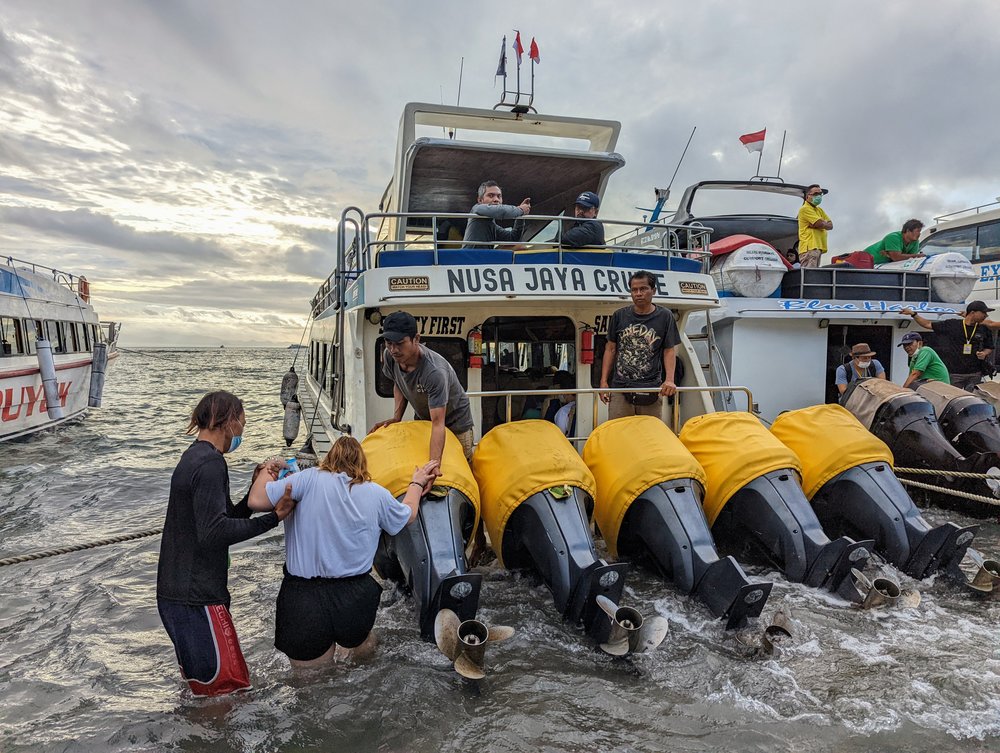 woman climbing on board a boat to nusa penida from bali