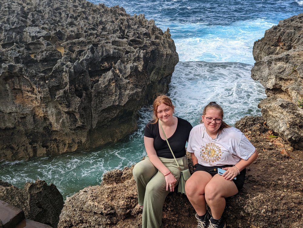 two white girls witting on a rock by the sea at nusa penida