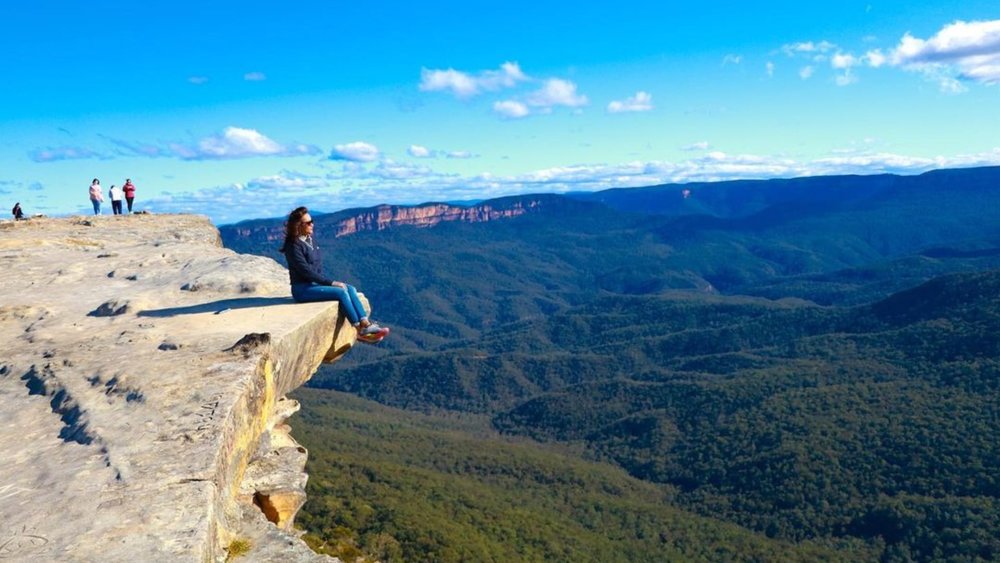 Girl posing for a photo while sitting on the edge of the cliff of Blue Mountains