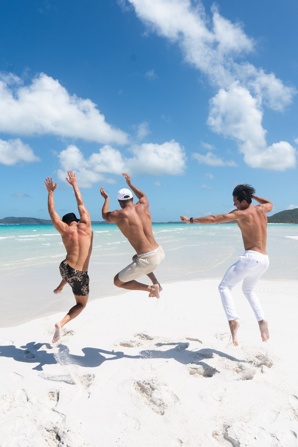 Three guys doing a jump shot on the beach