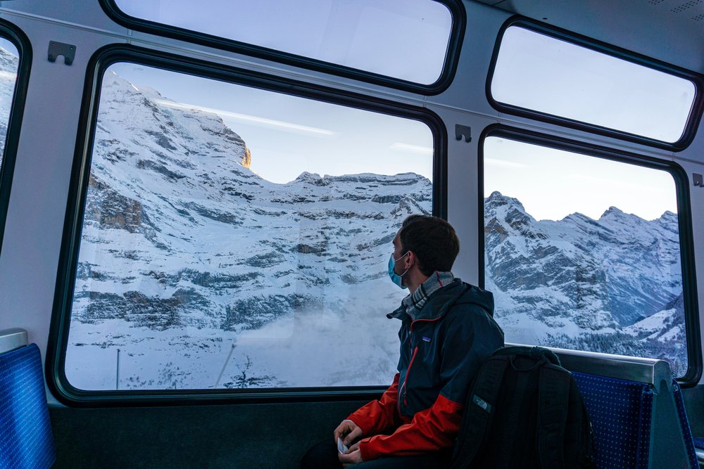 Man looking at snowy mountains from a train in Switzerland