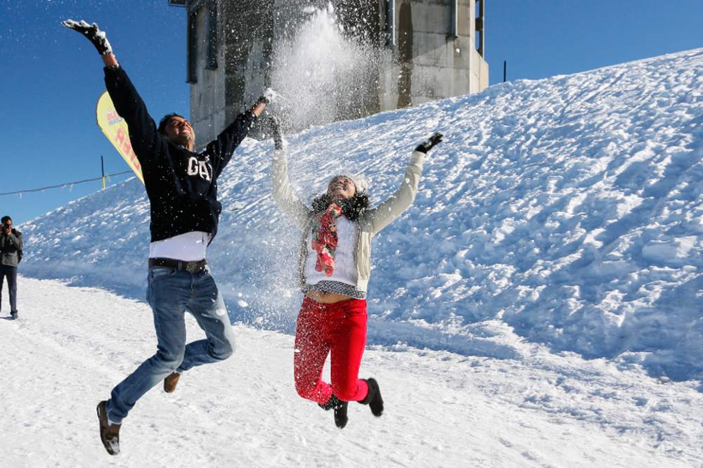 people jumping for joy and playing with snow on mount titlis