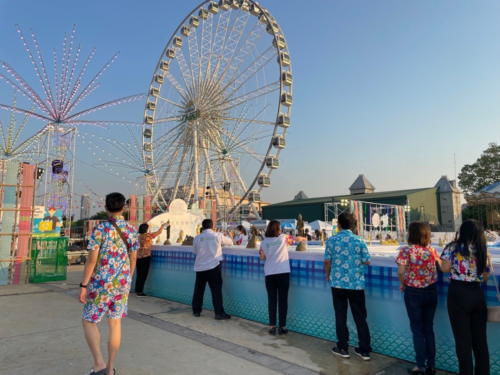 People in a carnival infront of ferris wheel
