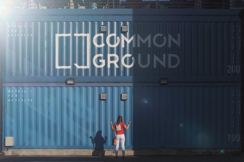 Girl posing for a photo in front of Common Ground containers