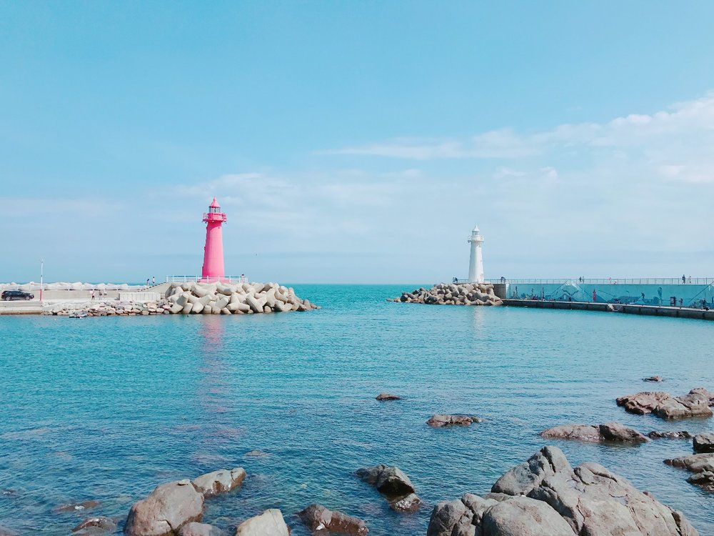 Pink and white lighthouse towers standing on a rock formation over the sea