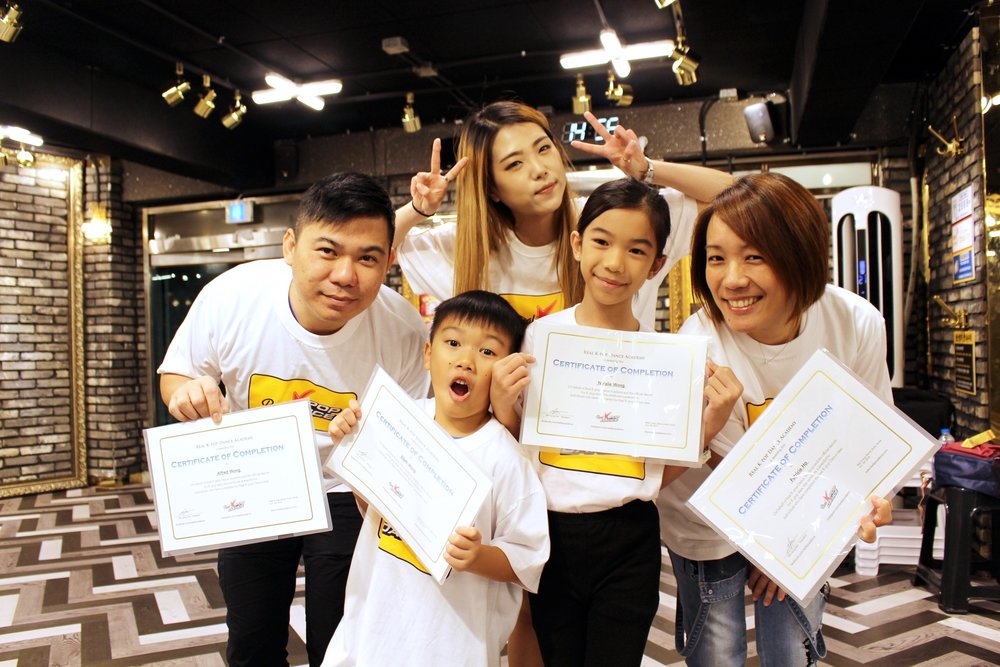 Family holding individual certificates with their dance instructor