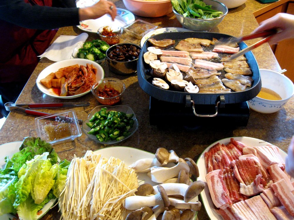 Korean barbecue table spread with meat, kimchi, and vegetables