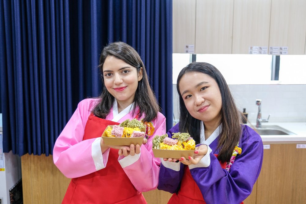 Two girls smiling at the camera while holding their yeot-gangjeong