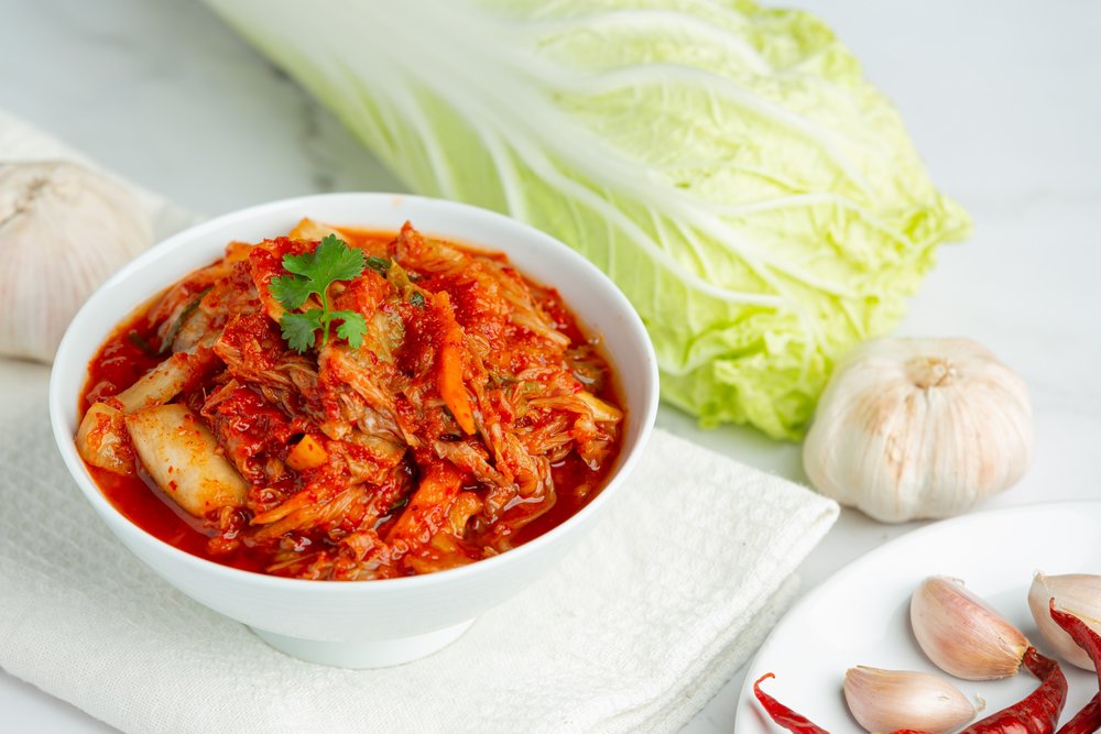 Fresh ingredients beside a bowl of kimchi