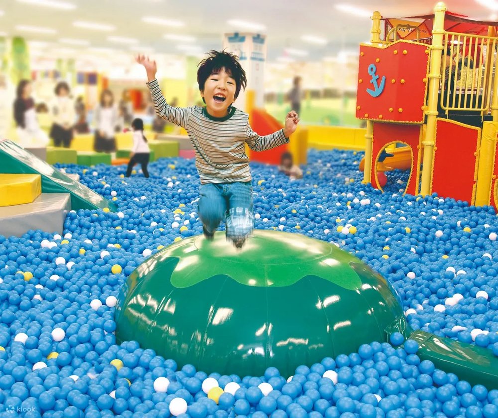 Kid playing inside a pool full of blue balls