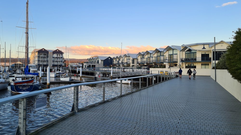 People walking on a bridge surrounded by houses and boats