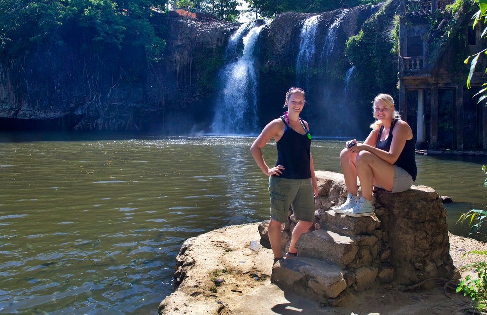 Two ladies smiling for a photo in front of Mena Creek Falls