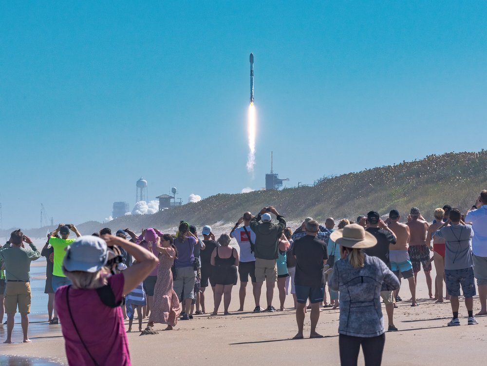 People watching a rocket launch on the beach