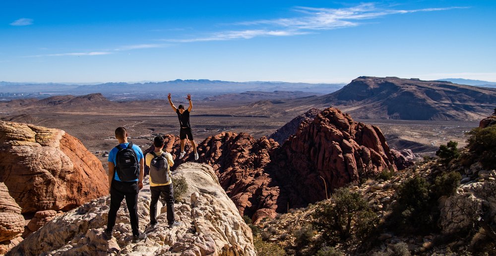 Three guys taking photos at the peak of a mountain