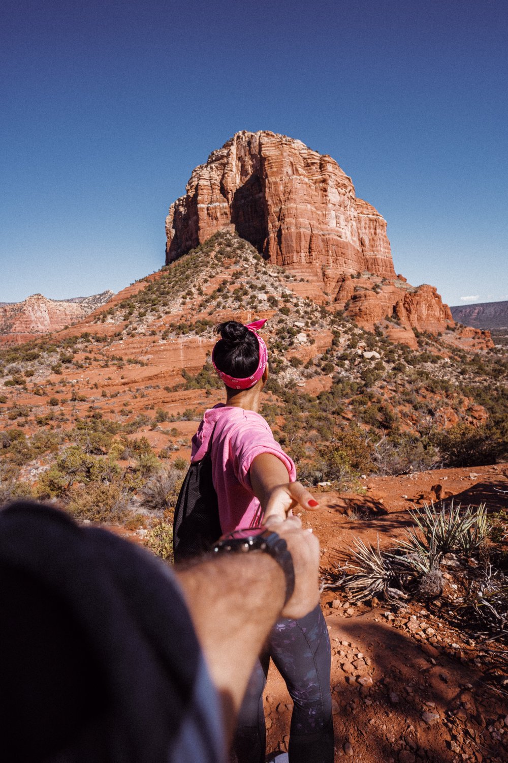 Woman in pink holding a man's hand while looking at the mountains