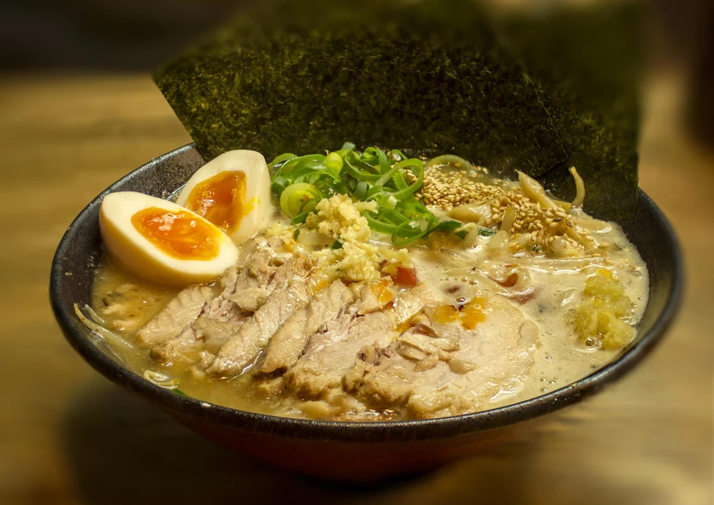 A bowl of ramen with noodles, soup, seaweed, meat, and eggs