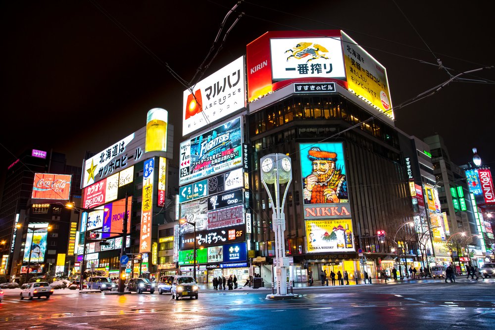 Streets with car, people, and many well-lit signage boards