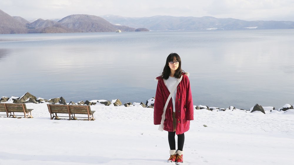 Girl in a red coat standing in front of Lake Toya