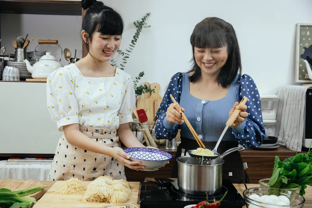 two girls happily making udon