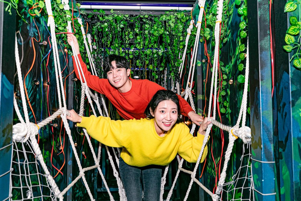 Man in red and woman in yellow walking on ropes inside a maze at Dynamic Maze