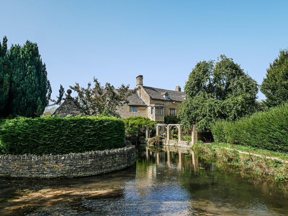 Body of water and greenery surrounding a house at The Cotswolds